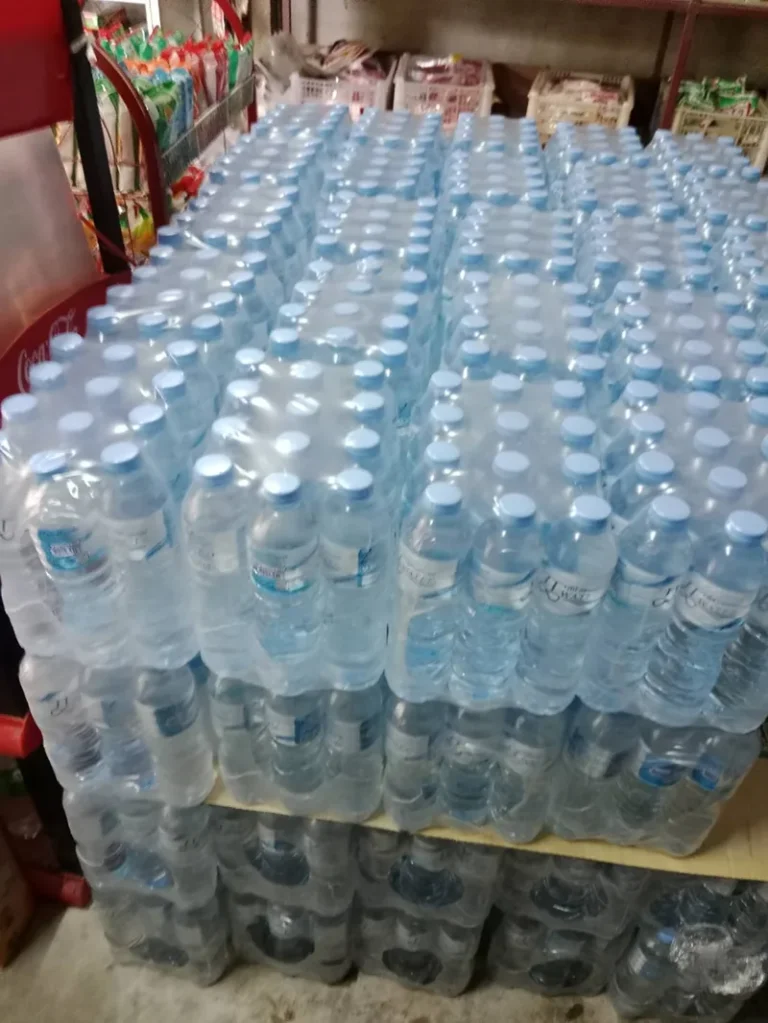 บริการ ส่งน้ำดื่ม มข กังสดาล - หลัง มข. น้ำดื่มราคาส่ง ส่งไวถึงหอพักและร้านอาหาร 9 ขวดน้ำที่บรรจุแล้วเรียงเป็นตั้งๆ ภายในโรงงาน